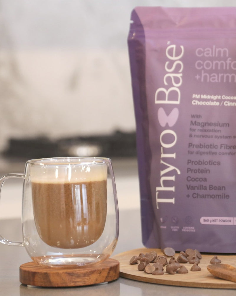 The finished ThyroBase PM drink, a warm cocoa in a glass mug beside the PM pouch.