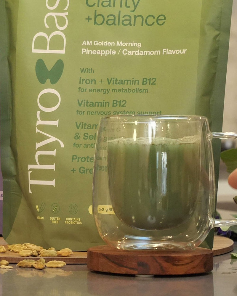The finished ThyroBase AM drink, a green glass beside the AM pouch.