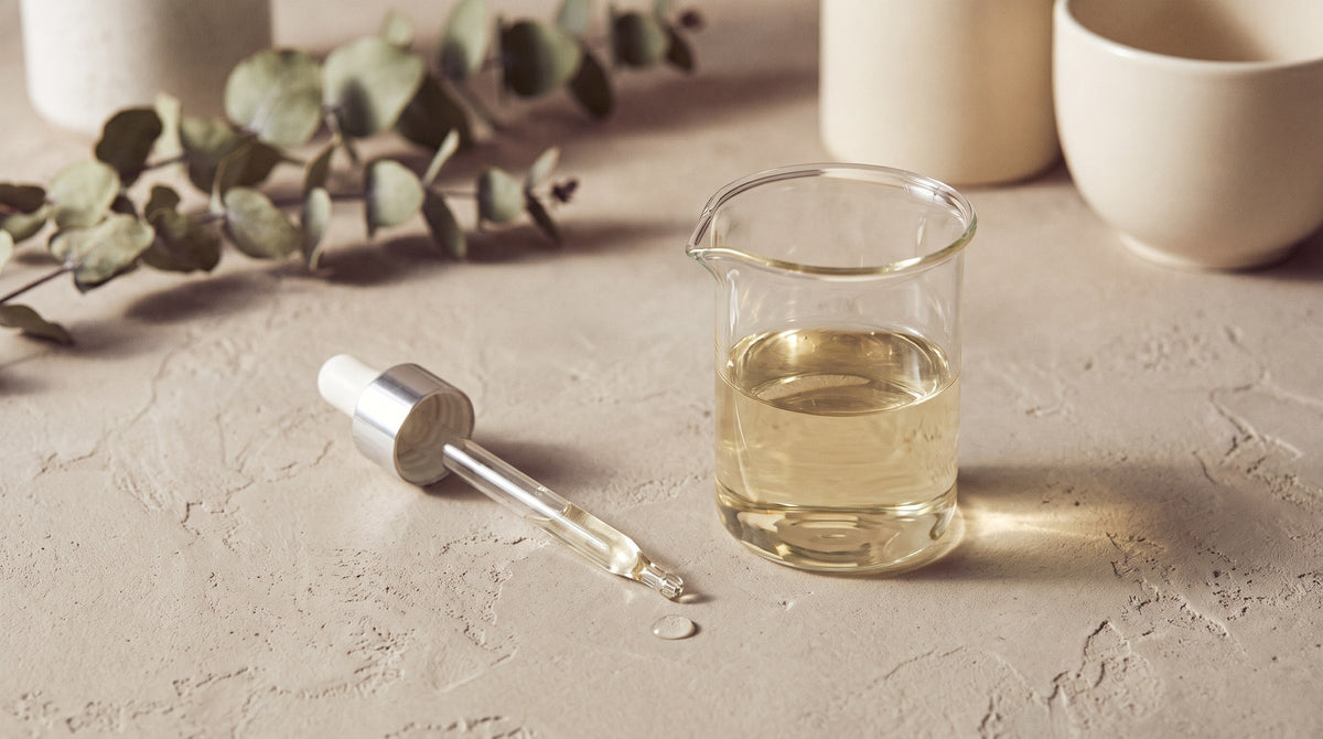 A glass beaker and pipette with a suspended drop of water in soft, diffused light