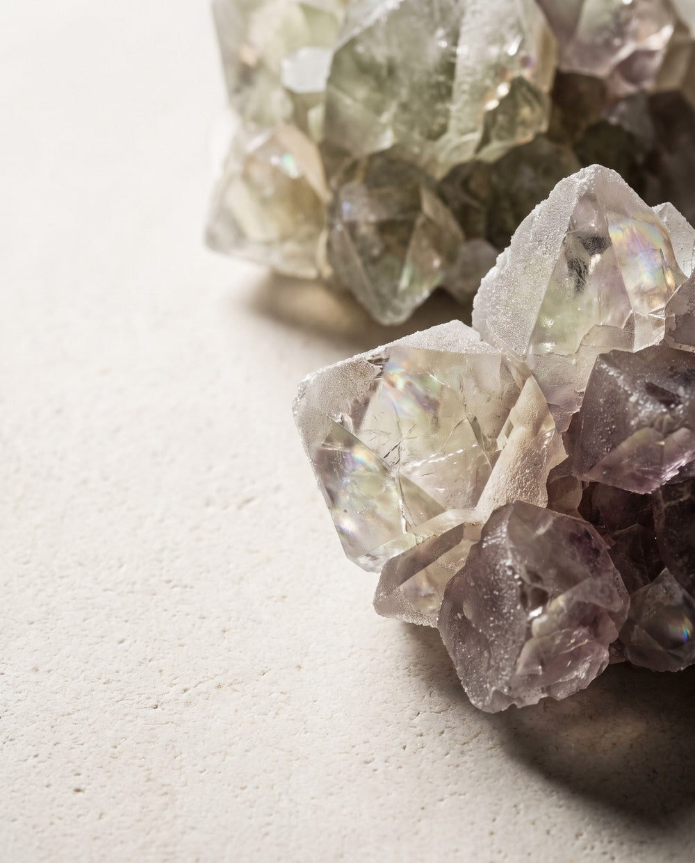 A translucent mineral crystal cluster resting on pale stone